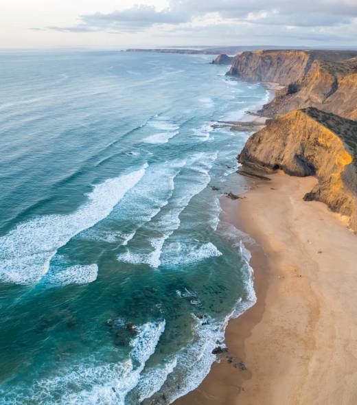 Sunset over amazing Cordoama sandy beach in Portugal. Aerial drone view.